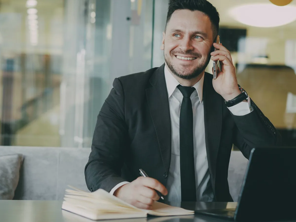 A title agent taking a call at a desk, making a note