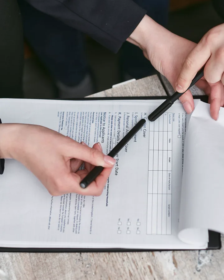 Two people going through the closing documents, one marking a page with a pen