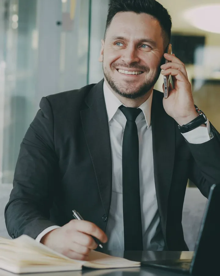 A closing coordinator taking a call at his desk, making a note