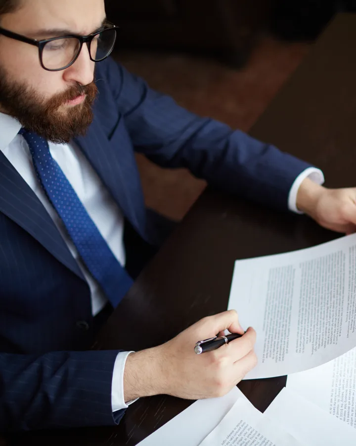 A title professional reading closely through a contract, papers spread across the table
