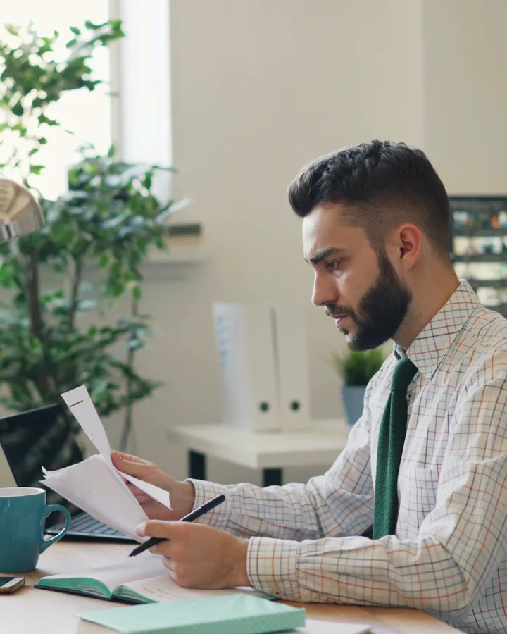 A title professional reading through a file at his desk